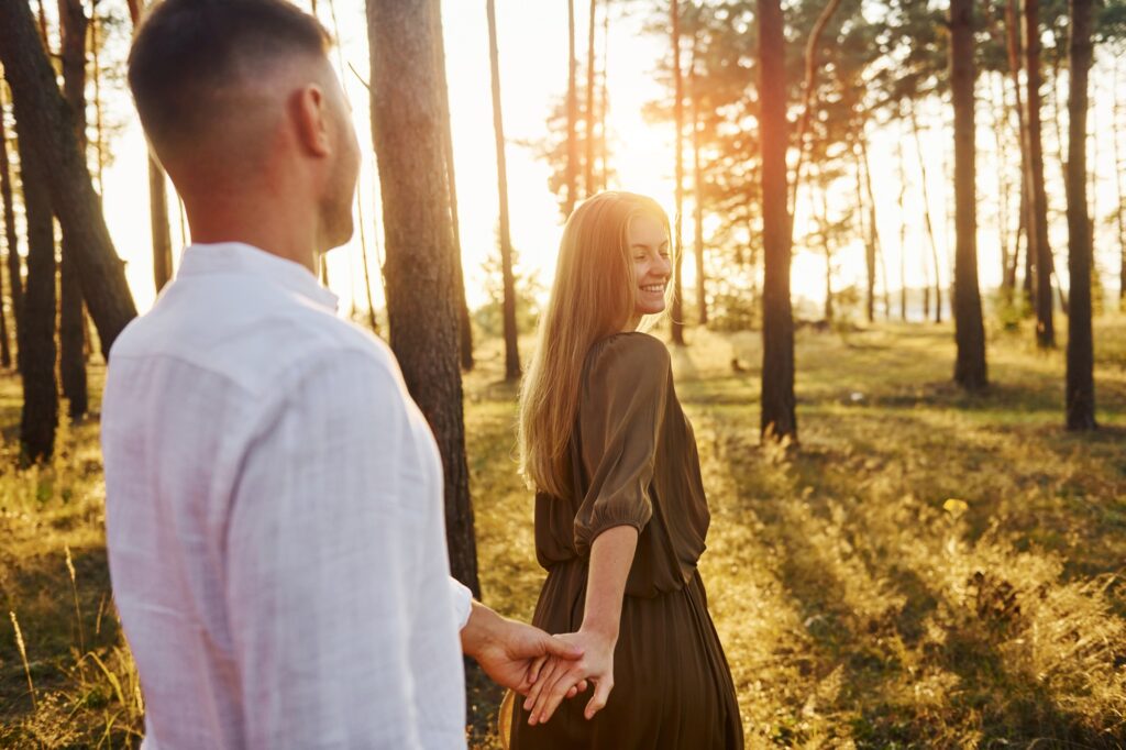 Follow me, concept. Happy couple is outdoors in the forest at daytime